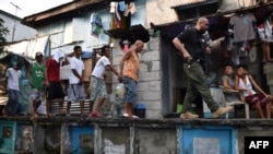 រូបឯកសារ៖ ភ្នាក់​ងារ​អនុវត្ត​ច្បាប់​គ្រឿង​ញៀន​របស់​ហ្វីលីពីន​កំពុង​នាំ​ជន​សង្ស័យ​រឿង​គ្រឿង​ញៀន​ក្នុងពេល​បង្ក្រាប​មួយ​នៅ​តំបន់​សំណង់​អនាធិបតេយ្យ នៅ​កន្លែង​បញ្ចុះ​សព​មួយកន្លែង​​ក្នុង​ទីក្រុង​ម៉ានីល កាល​ពី​ខែ​មីនា។