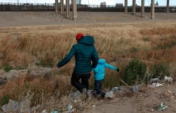 A Guatemalan migrant and his son cross the Rio Grande natural border between El Paso, state of Texas, US, and Ciudad Juarez, Chihuahua state, Mexico in search of political asylum on January 26, 2021. (Photo by HERIKA MARTINEZ / AFP)