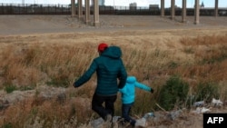 A Guatemalan migrant and his son cross the Rio Grande natural border between El Paso, state of Texas, U.S., and Ciudad Juarez, Chihuahua state, Mexico, in search of political asylum Jan. 26, 2021. 