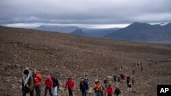 People climb to the top of what once was the Okjokull glacier, in Iceland, Aug. 18, 2019.