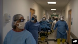 បុគ្គលិក​សុខាភិបាល​រុញ​អ្នក​ជំងឺ​កូវីដ១៩​ដើម្បី​យក​ទៅ​ព្យាបាល​នៅ​មន្ទីរពេទ្យ Dr. Ernesto Che Guevara នៅ​ក្នុង​ក្រុង Marica ប្រទេស​ប្រេស៊ីល កាលពី​ថ្ងៃទី២១ ខែឧសភា ឆ្នាំ២០២០។