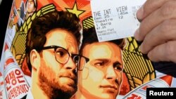 FILE - Dennis Lavalle holds a ticket and a poster of the film "The Interview," starring actors Seth Rogen and James Franco.