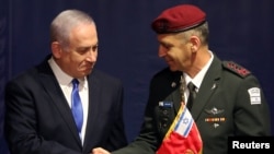 Israeli Prime Minister Benjamin Netanyahu shakes hands with incoming Israeli Chief of Staff Aviv Kohavi during a ceremony whereby he replaces Lieutenant-General Gadi Eizenkot, at the Defense Ministry in Tel Aviv, Jan. 15, 2019. 