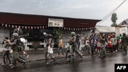 Members of the M23 armed group walk alongside residents through a street of the Keshero neighborhood in Goma, on Jan. 27, 2025. 