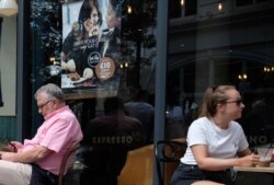 Customers eat at restaurant in central London, Aug. 3, 2020, next to signs indicating a discount off food. Restaurant discount meals "Eat out to help out" is a government run program.