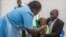FILE - A health worker administers a typhoid vaccine dose to a boy, as his father holds him, during a typhoid vaccination drive at Ndirande Health Centre in Blantyre, Malawi, Feb. 21, 2018.