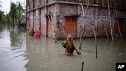 Villagers wade through waist-deep waters to reach their homes in Pratap Nagar that lies in the Shyamnagar region, in Satkhira, Bangladesh on Oct. 5, 2021. (AP Photo/Mahmud Hossain Opu)