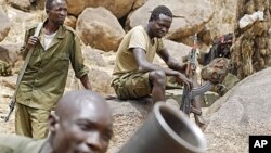 FILE - SPLA-N fighters practice with a mortar as others watch near Jebel Kwo village in the rebel-held territory of the Nuba Mountains in South Kordofan, Sudan May 2, 2012.