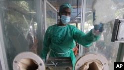 An employee cleans a booth at a testing and screening facility for the new coronavirus, in a hospital in Karachi, Pakistan, July 17, 2020.