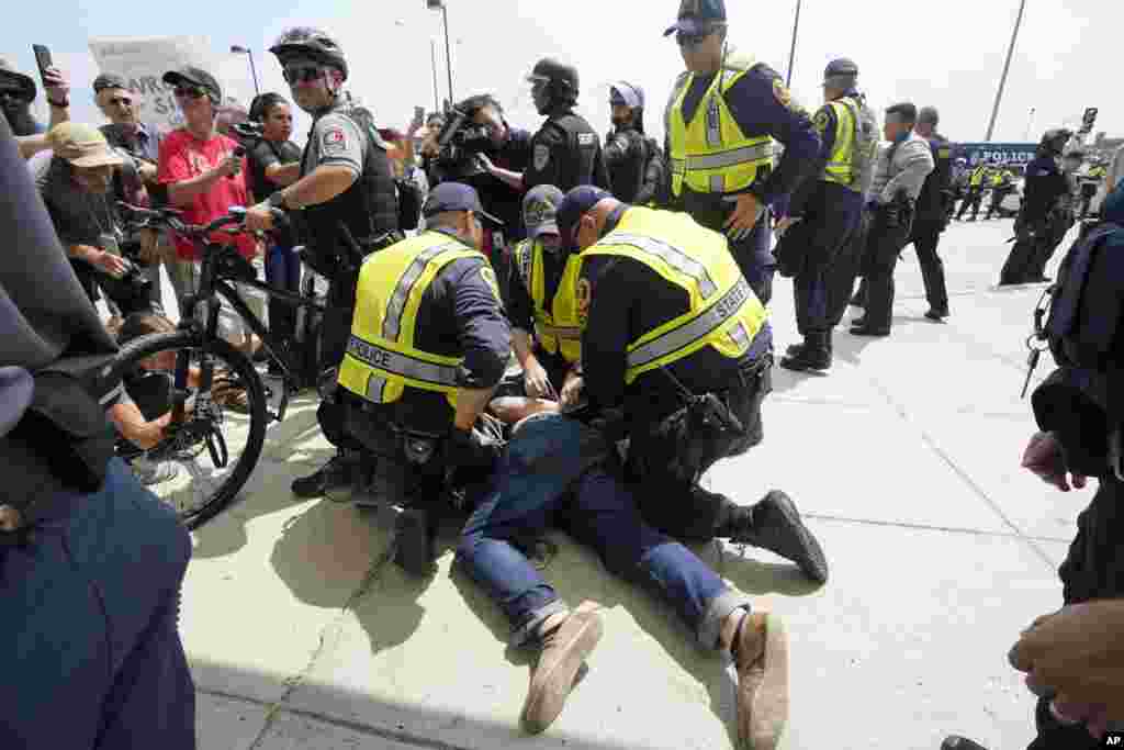 A man is detained while white supremacist Jason Kessler arrives at the Vienna metro station in Vienna, Va., Sunday, Aug. 12, 2018. White nationalists are gathering in Washington on the first anniversary of their rally in Charlottesville. 
