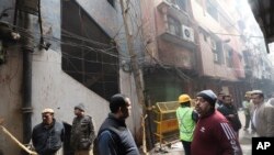 Policemen and neighbors stand in front of an ill-fated building which caught fire on Sunday, in New Delhi, India, Monday, Dec. 9, 2019. Authorities say an electrical short circuit appears to have caused a devastating fire that killed dozens of…
