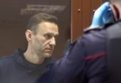 Kremlin critic Alexey Navalny stands inside a defendant dock before a court hearing in Moscow, Feb. 5, 2021.
