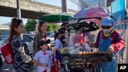 Schoolchildren gather around street vendors outside their school in Bangkok, Thailand, Nov. 1, 2018. 