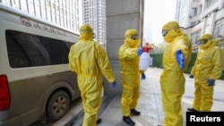 Petugas rumah duka (mengenakan pakaian pelindung), membantu koleganya menyemprotkan pembasmi kuman seusai memindahkan jenazah pasien yang terinfeksi virus corona dari rumah sakit di Wuhan, provinsi Hubei, China, 30 Januari 2020.

