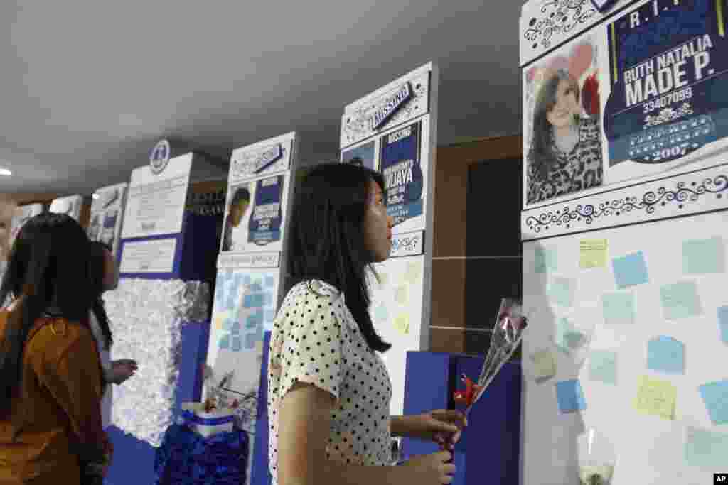 A student of Petra Christian University holds a flower near the memorial walls for their friends who were on board the ill-fated AirAsia Flight 8501, in Surabaya, East Java, Indonesia, Jan. 14, 2015.