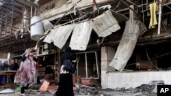 FILE - Iraqis inspect the aftermath a day after a car bomb attack in a shopping area in Karradah, Baghdad, Iraq, Aug. 1, 2012. 
