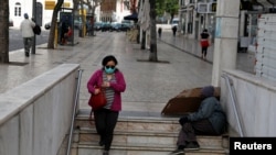 FILE - A woman wearing a mask as a preventive measure against the coronavirus enters a subway station at Rossio Square in downtown Lisbon, Portugal, March 19, 2020. 