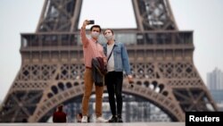 Wisatawan mengenakan masker, berfoto selfie di alun-alun Trocadero dekat Menara Eiffel di Paris, Perancis, 16 Mei 2020. (Foto: dok).