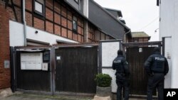 Police officers are standing in front of an apartment building in Erfurt, Germany, Jan. 23, 2020. Germany's top security official has announced a ban on the neo-Nazi group 'Combat 18' Deutschland. 