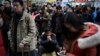 A man, center, sits on his belonging as he waits with other Chinese traveler to board a at the south train station in Beijing, Jan. 31, 2016.