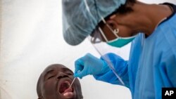 A man opens his mouth for a heath worker to collect a sample for coronavirus testing during the screening and testing campaign aimed to combat the spread of COVID-19 Diepsloot, north Johannesburg, South Africa, May 8, 2020.