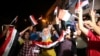 Iraqis celebrate while holding national flags in Tahrir square in Baghdad, Iraq, July 10, 2017. Prime Minister Haider al-Abadi declared victory against the Islamic State group in Mosul.