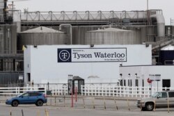 FILE - Vehicles sit in an almost empty parking lot outside the Tyson Foods plant in Waterloo, Iowa, May 1, 2020.