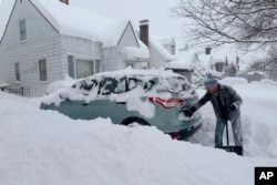 ریاست نیویارک کے شہر بفلو میں ایک شخص اپنی گاڑی نکالنے کے لیے اس پر جمی برف ہٹا رہا ہے۔ 17 جنوری 2024