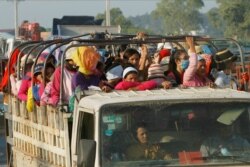 Cambodian garment factory workers ride on the back of a truck as they head to their factory outside Phnom Penh, Oct. 26, 2019.