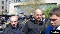 Pengamat OSCE Axel Schneider (tengah) dikawal ketat seusai dibebaskan oleh separatis pro-Rusia yang menahannya sejak bulan lalu di kota Slaviansk, Ukraina Timur (3/5).