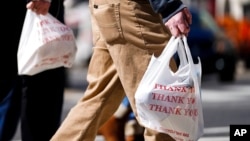 FILE - Pedestrians carry plastic bags in Philadelphia, March 3, 2021. Giving out single-use plastic bags in the city became illegal this fall, but penalties don’t start until April 1.