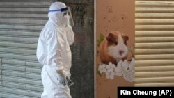 Seorang petugas kesehatan Hong Kong melewati sebuah toko hewan piaraan yang saat ini ditutup karena kekhawatiran ribuan hewan yang positif COVID-19, Selasa (18/1). 