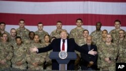 Presiden Donald Trump (tengah) bersama Presiden Afghanistan Ashraf Ghani dan Kepala Staf Gabungan Militer AS Jenderal Mark Milley (di belakangnya, kanan), dalam kunjungan kejutan Hari Thanksgiving di bandara Bagram, Afghanistan, Kamis, 28 November 2019.