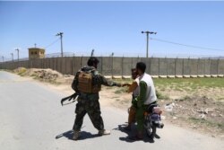 بگرام ایئر پورٹ کے قریب ایک افغان فوجی وہاں سے گزرنے والے موٹرسائیکل سواروں سے پوچھ گچھ کر رہا ہے۔ 2 جولائی 2021