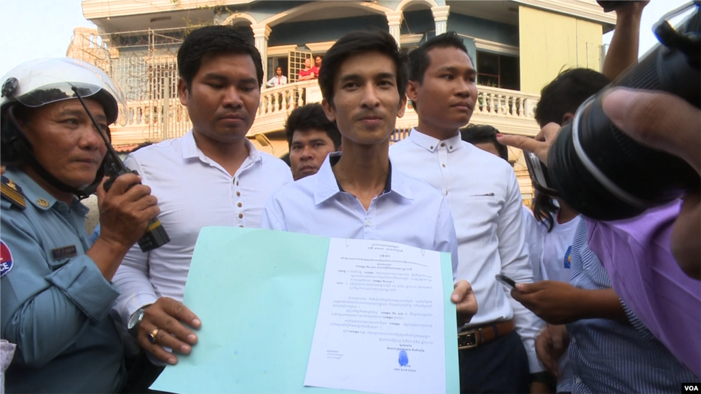 Srey Chamroeun, who led students group dressing in CNRP&#39;s uniform, shows his petition to journalists. (Leng Len/VOA Khmer). &nbsp;