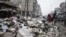 A family crosses a street piled with garbage in Aleppo, Syria, January 5, 2013.