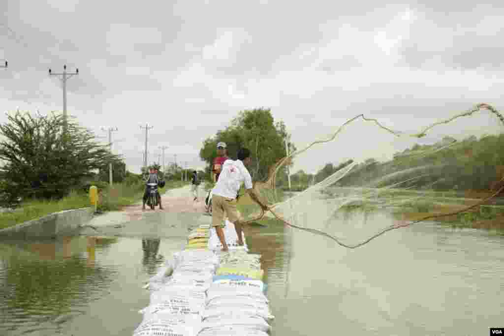 បុរសម្នាក់​កំពុង​បង់សំណាញចាប់ត្រីពីទឹកស្ទឹងព្រែកត្នោត ដែលបានលិចជោរជន់ដោយទឹកភ្លៀង នៅសង្កាត់ព្រែកកំពឹស ខណ្ឌដង្កោរ ភ្នំពេញ ថ្ងៃទី១៤ ខែតុលា ឆ្នាំ២០២០។ (ទុំ ម្លិះ/វីអូអេ)