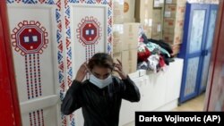 In this photo taken Wednesday, Oct. 28, 2020, a girl puts on her mask in Svratiste, or Roadhouse, Belgrade's first daily drop-in center for street children, in Serbia. (AP Photo/Darko Vojinovic)