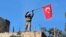 Seorang tentara mengibarkan bendera Turki setelah militer Turki berhasil menguasai bukit Bursayah, yang memisahkan kota Afrin, Suriah yang dikuasai milisi Kurdi, dengan kota Azaz yang dikuasai Turki (28/1). 