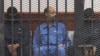 FILE - Saif al-Islam Gadhafi in the accused cell as he stands trial for illegally trying communicating with the outside world in June of 2012, Zintan, Libya, May 2, 2013.