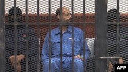 FILE - Saif al-Islam Gadhafi in the accused cell as he stands trial for illegally trying communicating with the outside world in June of 2012, Zintan, Libya, May 2, 2013.
