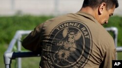 A member of the Border Patrol's Border Tunnel Entry Team looks on from a tunnel entrance in between two border barriers separating San Diego and Tijuana, Mexico, in San Diego, March 6, 2017.