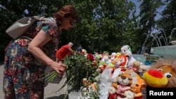 Seorang perempuan menaruh bunga di area memorial sementara di Sevastopol, Krimea, pada 24 Juni 2024. Memorial tersebut dibuat untuk mengenang korban dari serangan misil di Krimea, yang menurut otoritas Rusia dilakukan oleh Ukraina. (Foto: Reuters/Alexey Pavlishak) 