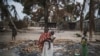 FILE - A woman holds her child while standing in a burned out area in the attacked village of Aldeia da Paz outside Macomia in Cabo Delgado province, in Mozambique, on Aug. 24, 2019.