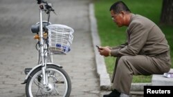 지난 10월 평양 시내에서 한 남성이 자전거를 세워놓고 휴대전화를 사용하고 있다. (자료사진)