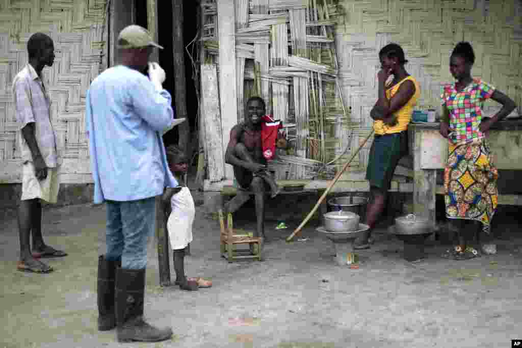 Mr. Kollis (center) who shows signs of possible Ebola infection, refuses to leave his home and board a District 13 ambulance dispatched to fetch him in Monrovia, Liberia, Sept. 30, 2014. 