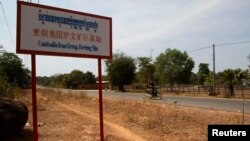 បុរស​ម្នាក់​បើក​​ម៉ូតូ​កាត់​ផ្លាក​ក្រុមហ៊ុន​ចិន Cambodia Iron Group នៅ​ស្រុក​រវៀង​ខេត្ត​ព្រះវិហារ​។ (រូបថត​ឯកសារ ១០ កុម្ភៈ ២០១៣)