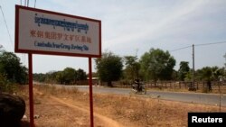 បុរស​ម្នាក់​ជិះ​ម៉ូតូ​កាត់​ផ្លាក​ក្រុមហ៊ុន​​​ Cambodia Iron Group នៅ​ស្រុក​រវៀង​ខេត្ត​ព្រះវិហារ កាល​ពី​ថ្ងៃ​ទី​១០​ខែ​កុម្ភៈ​ ឆ្នាំ​២០១៣។