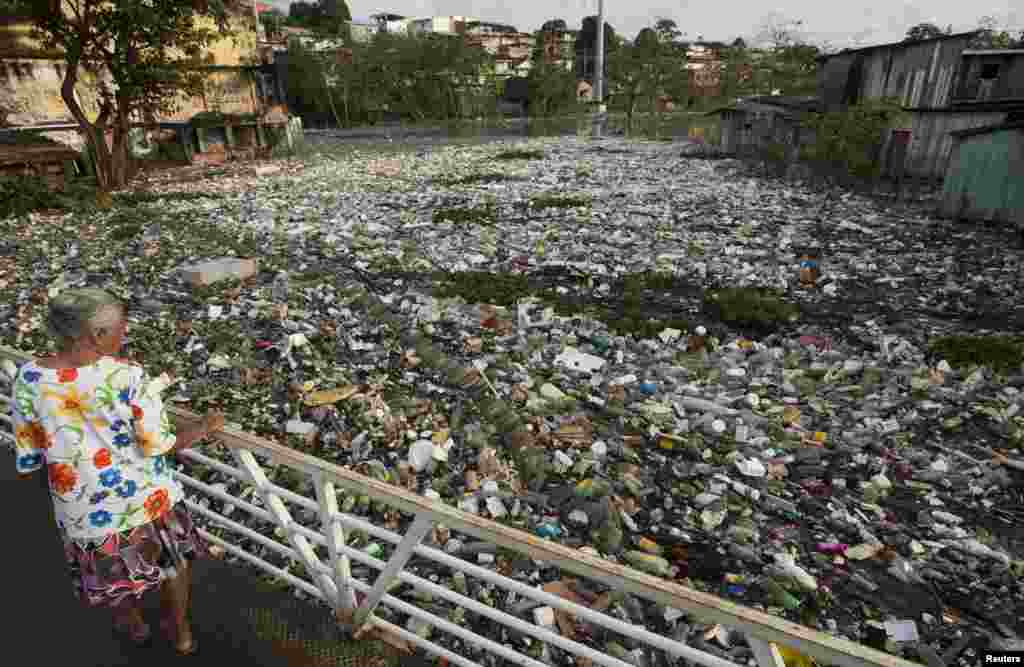 Seorang perempuan memandangi sampah-sampah yang tersapu akibat meluapnya sungai Negro, salah satu dari dua cabang utama Sungai Amazon, setelah hujan deras di Manaus, negara bagian Amazonas, Brazil, 22 Juni 2015.