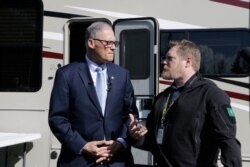 Washington Gov. Jay Inslee, left, talks with with Nathan Weed, incident commander for the coronavirus response team at Department of Health, outside a recreation vehicle at a potential coronavirus isolation and quarantine site, March 4, 2020.